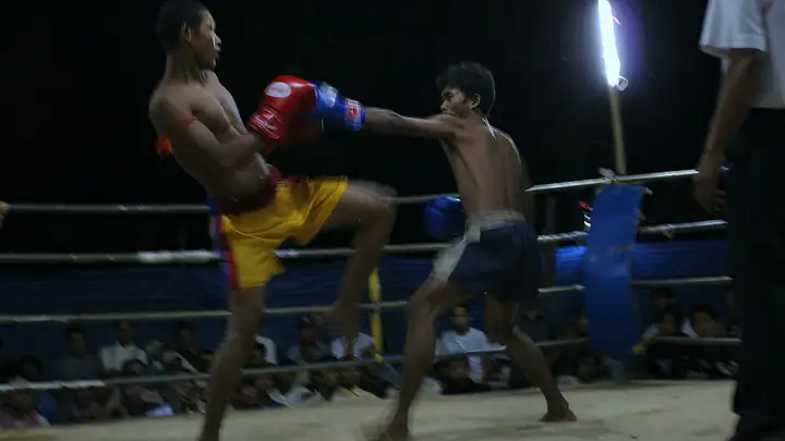 Two Kun Khmer fighters exchange strikes in an outdoor ring in Battambang, Cambodia