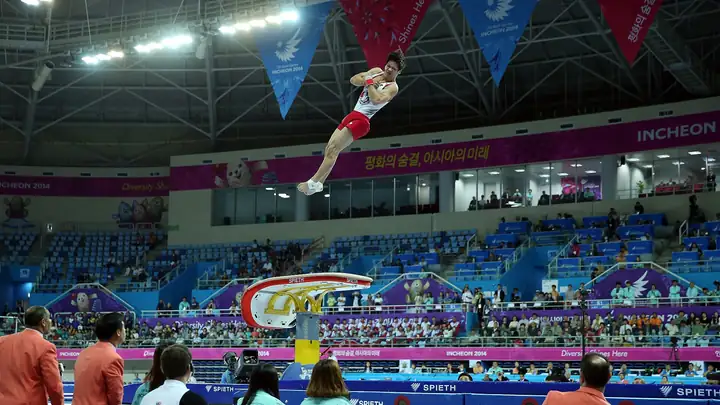 A gymnast flies high above the apparatus inside the gymnastics arena at the Incheon 2014 Asian Games